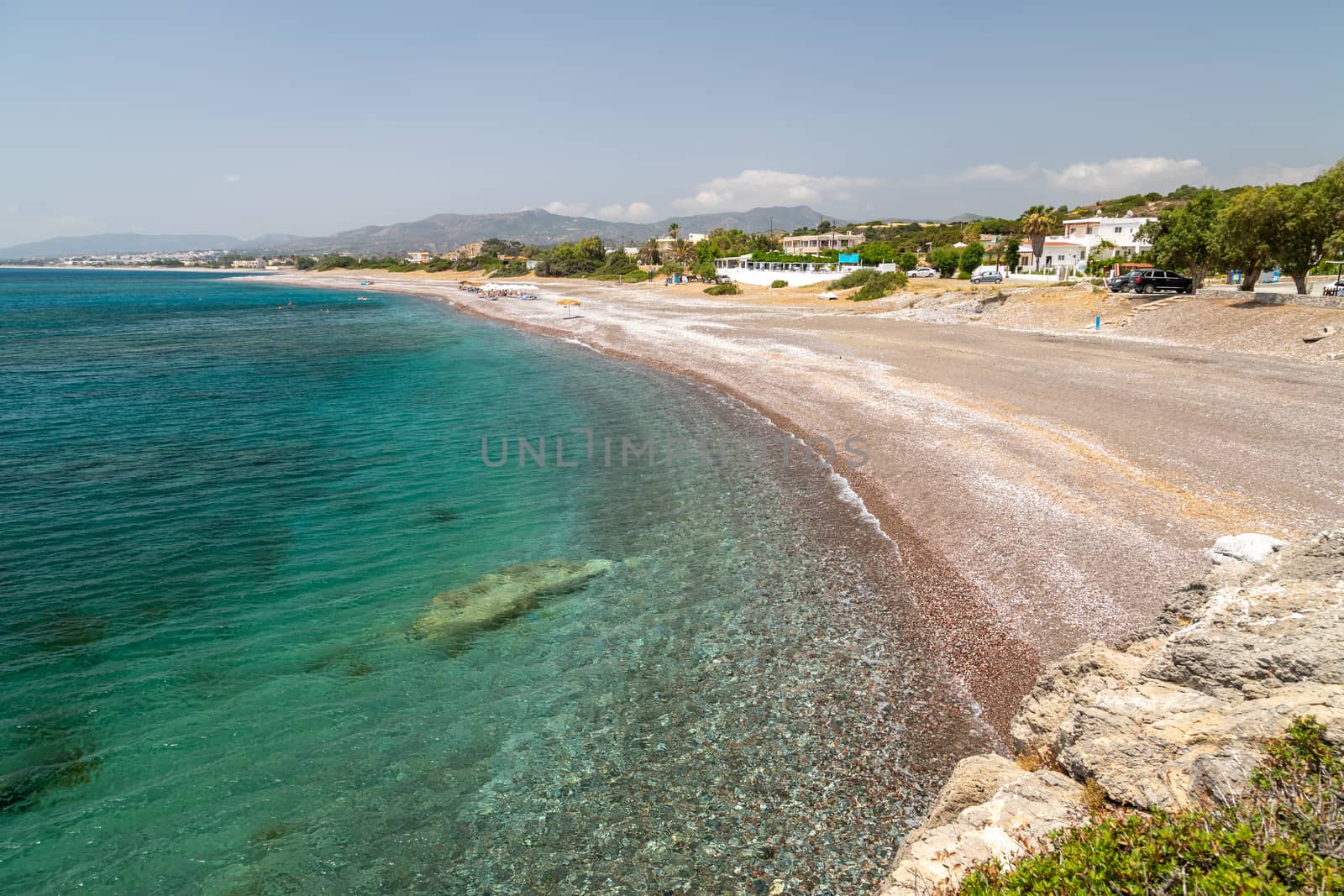 Gravel beach at Kiotari on Rhodes island, Greece with stones in different colours and turquoise clear water