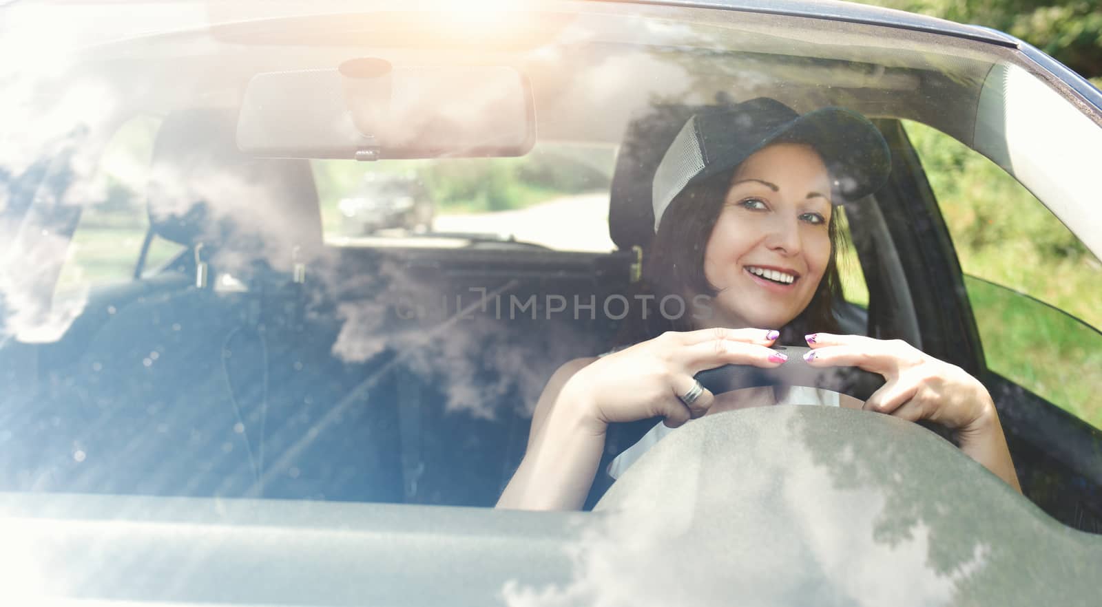 Beautiful adult happy woman driving her car in summer day