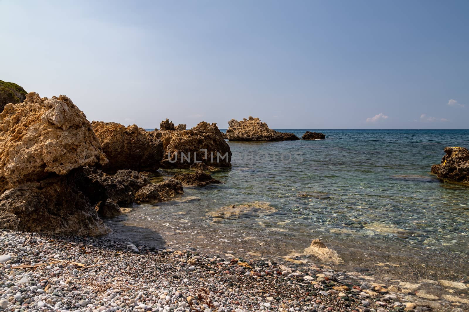 View at the rocky coastline of Plimmiri on  Rhodes island, Greece with gravel beach and rocks in the water