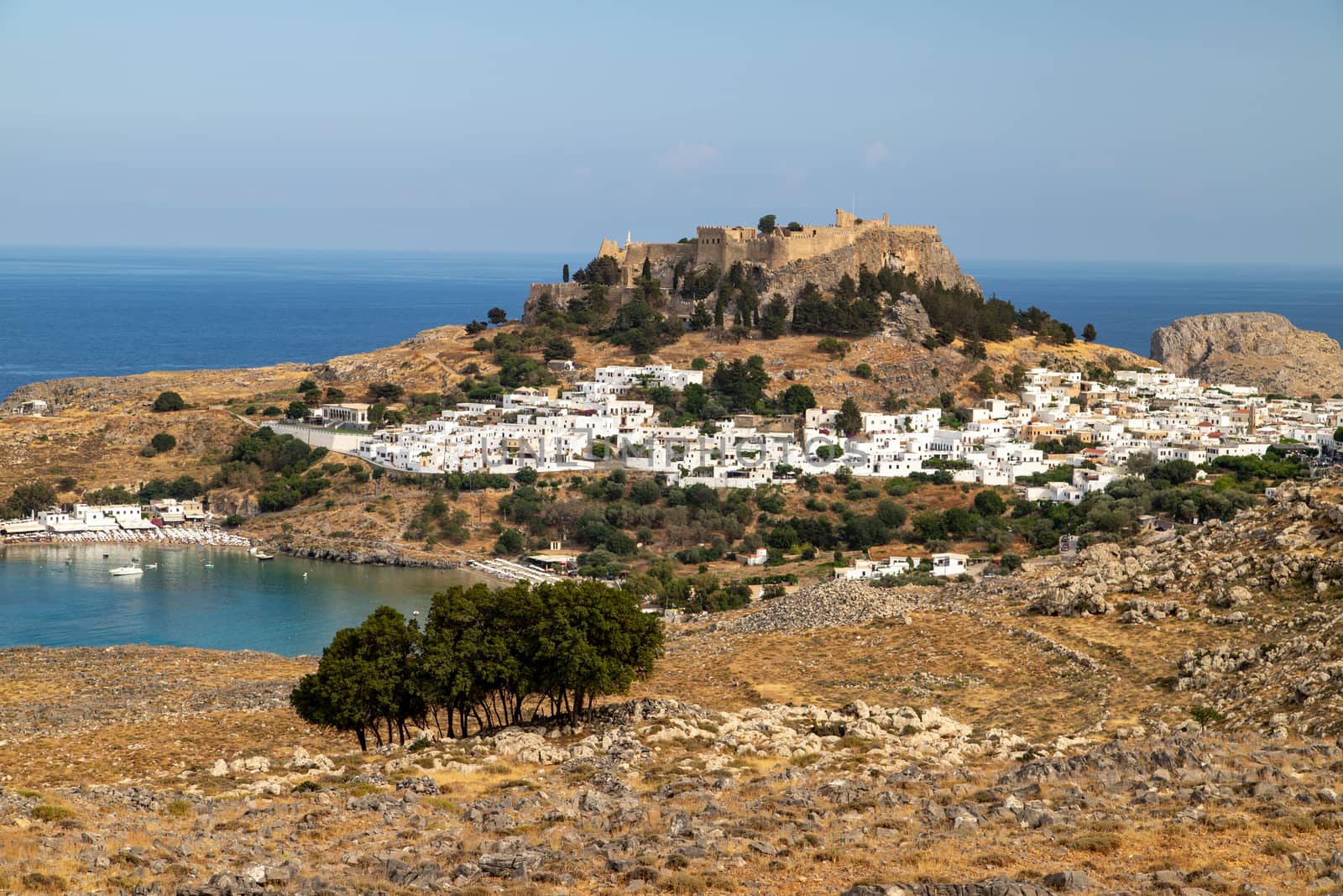 Scenic view at the city of Lindos with white houses, the antique Acropolis on top of the mountain and a bay on Rhodes island, Greece on a sunny day in spring