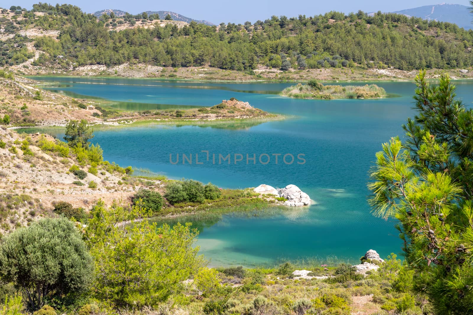 Scenic view at the Gadoura water reservoir on Rhodes island, Greece with blue and turquoise water and green landscape around the lake on a sunny day in spring