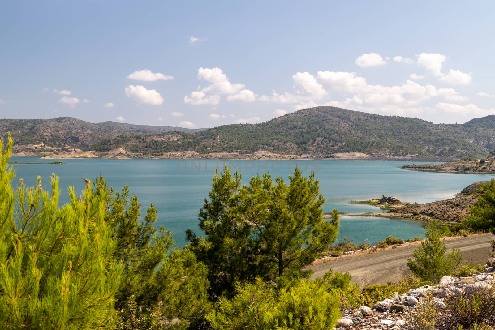 Scenic view at the Gadoura water reservoir on Rhodes island, Greece with blue and turquoise water and green landscape around the lake on a sunny day in spring