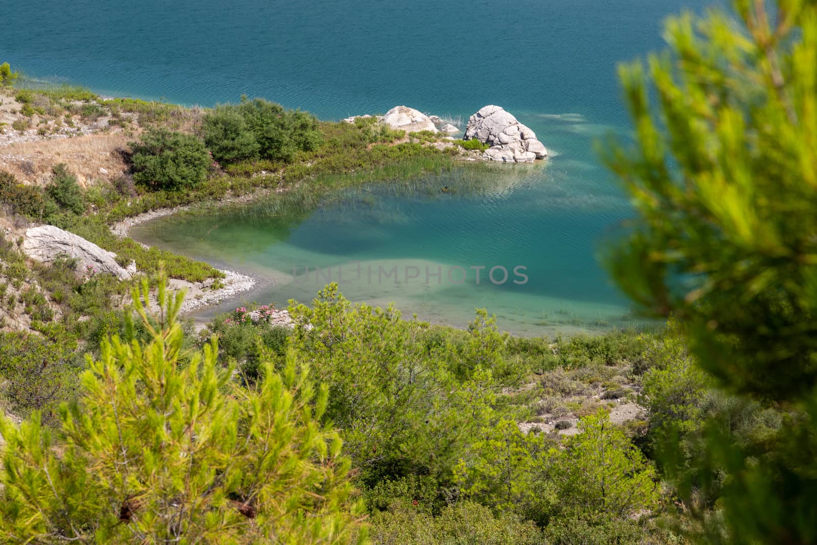 Scenic view at the Gadoura water reservoir on Rhodes island, Greece with blue and turquoise water and green landscape around the lake on a sunny day in spring