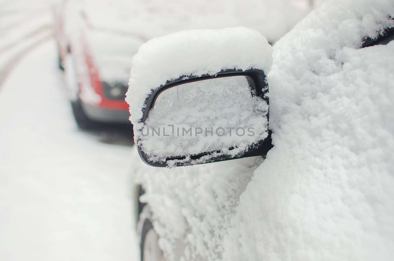 Car mirror filled with snow in winter season. White snow covered car side mirror. by KajaNi