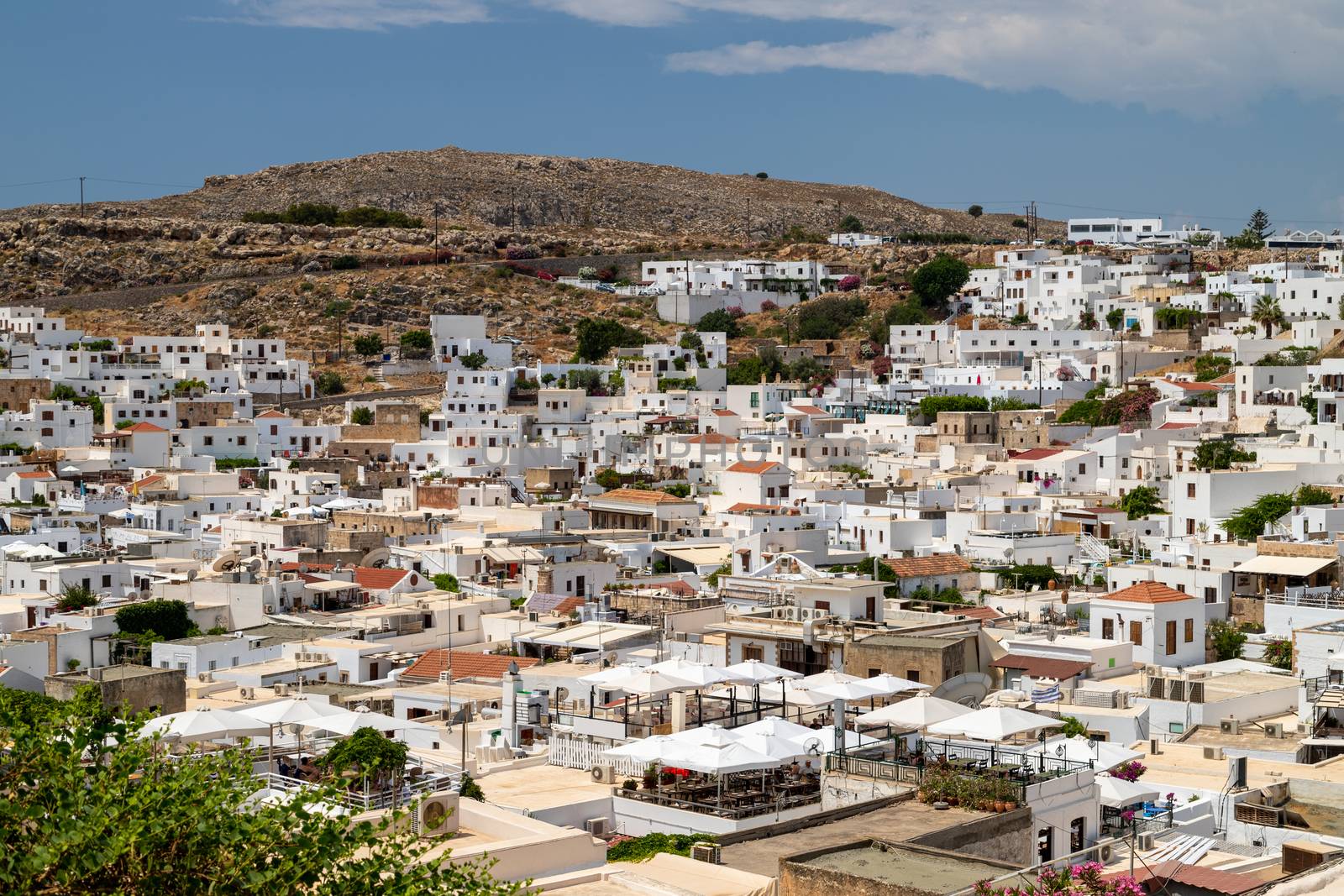 View at the city of Lindos on Greek island Rhodes with white houses and mountain in the background on a sunny day in spring