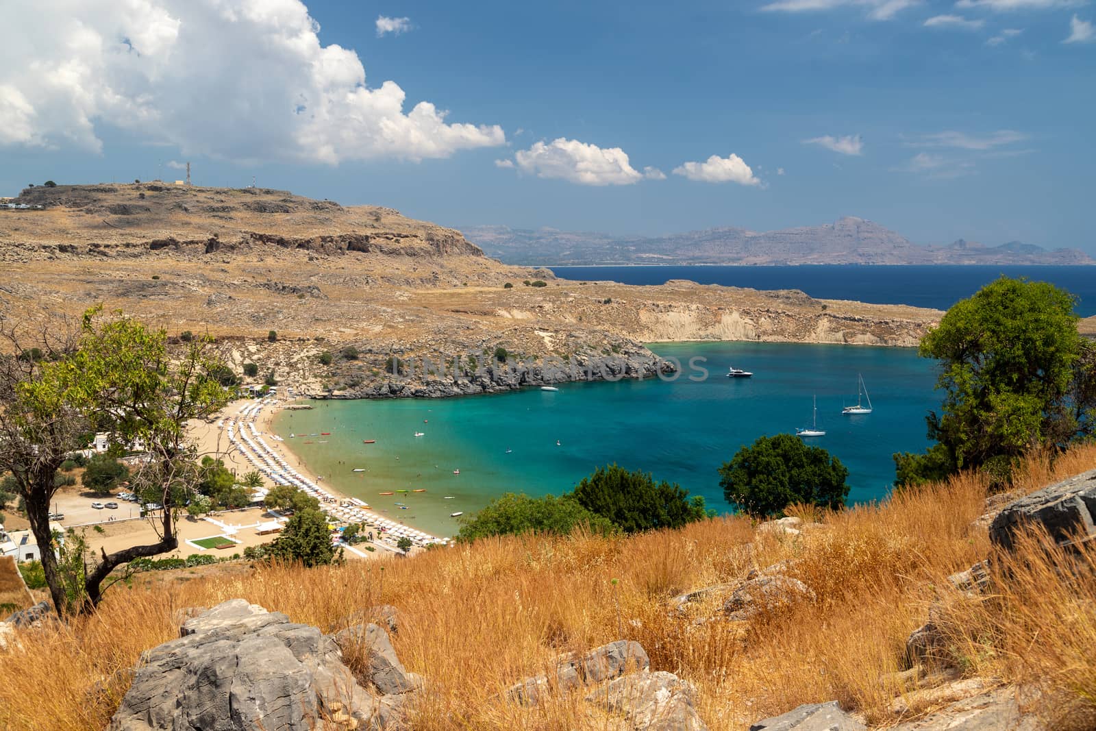 Scenic view from the acropolis on a bay and a beach with blue and turquoise water in Lindos on Rhodes island, Greece on a sunny day in spring