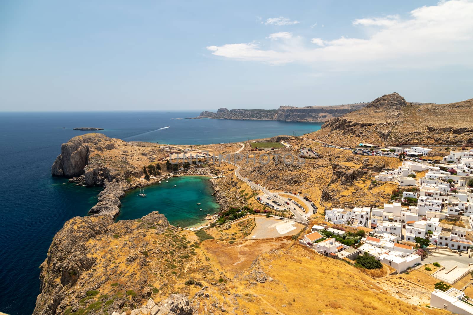 Scenic view from the acropolis of Lindos at the coastline of the mediterranean sea, the city of Lindos  and St. Pauls bay with clear and turquoise water