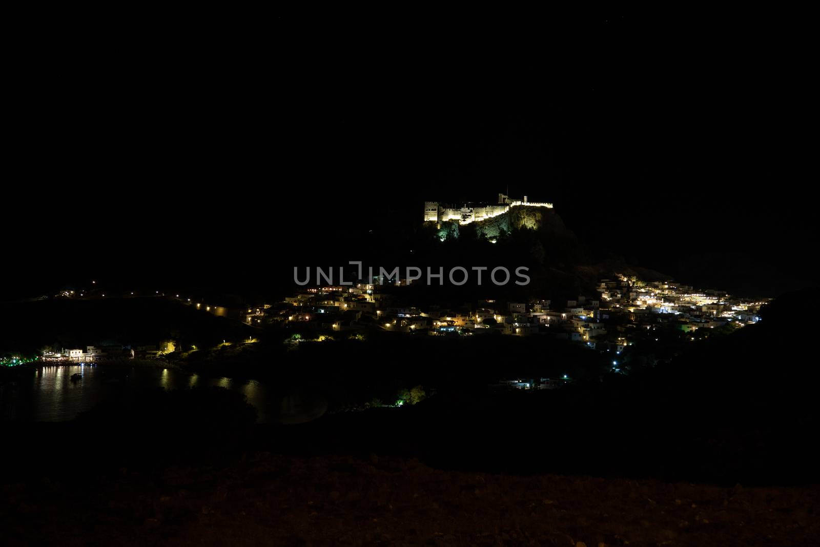 View at the illuminated city of Lindos and the acropolis on Greek island Rhodes by night
