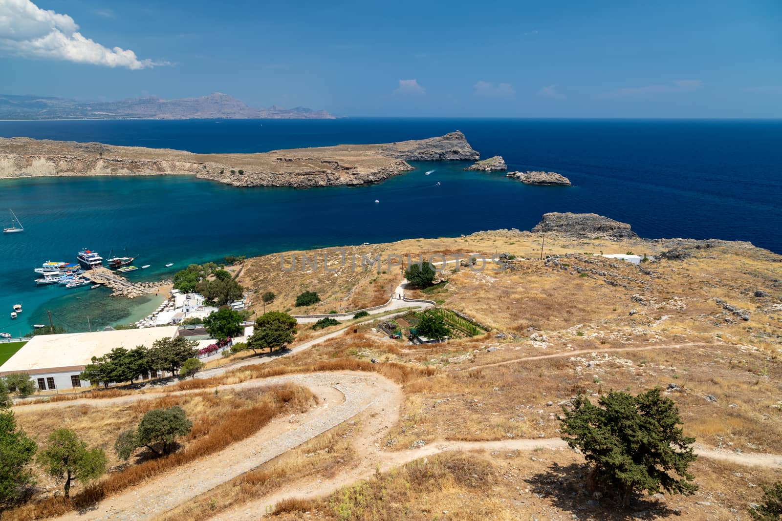 Scenic view from the acropolis on a bay and a beach with blue and turquoise water in Lindos on Rhodes island, Greece on a sunny day in spring