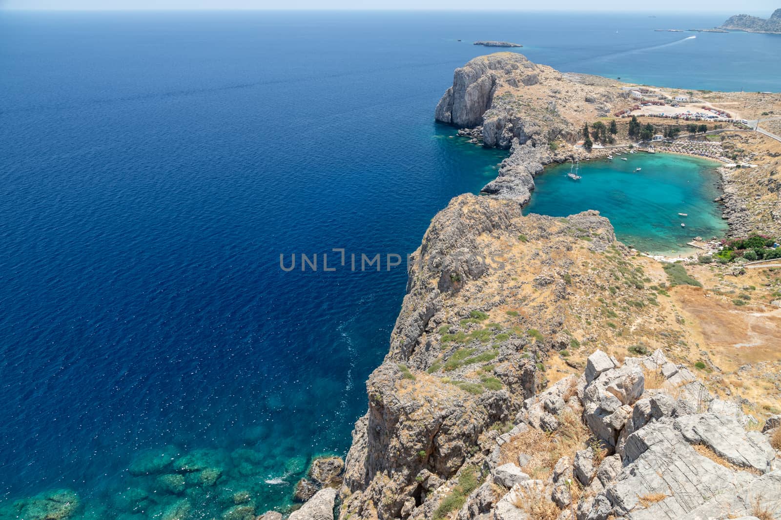 Scenic view from the acropolis of Lindos at the coastline of the mediterranean sea and St. Pauls bay with clear and turquoise water