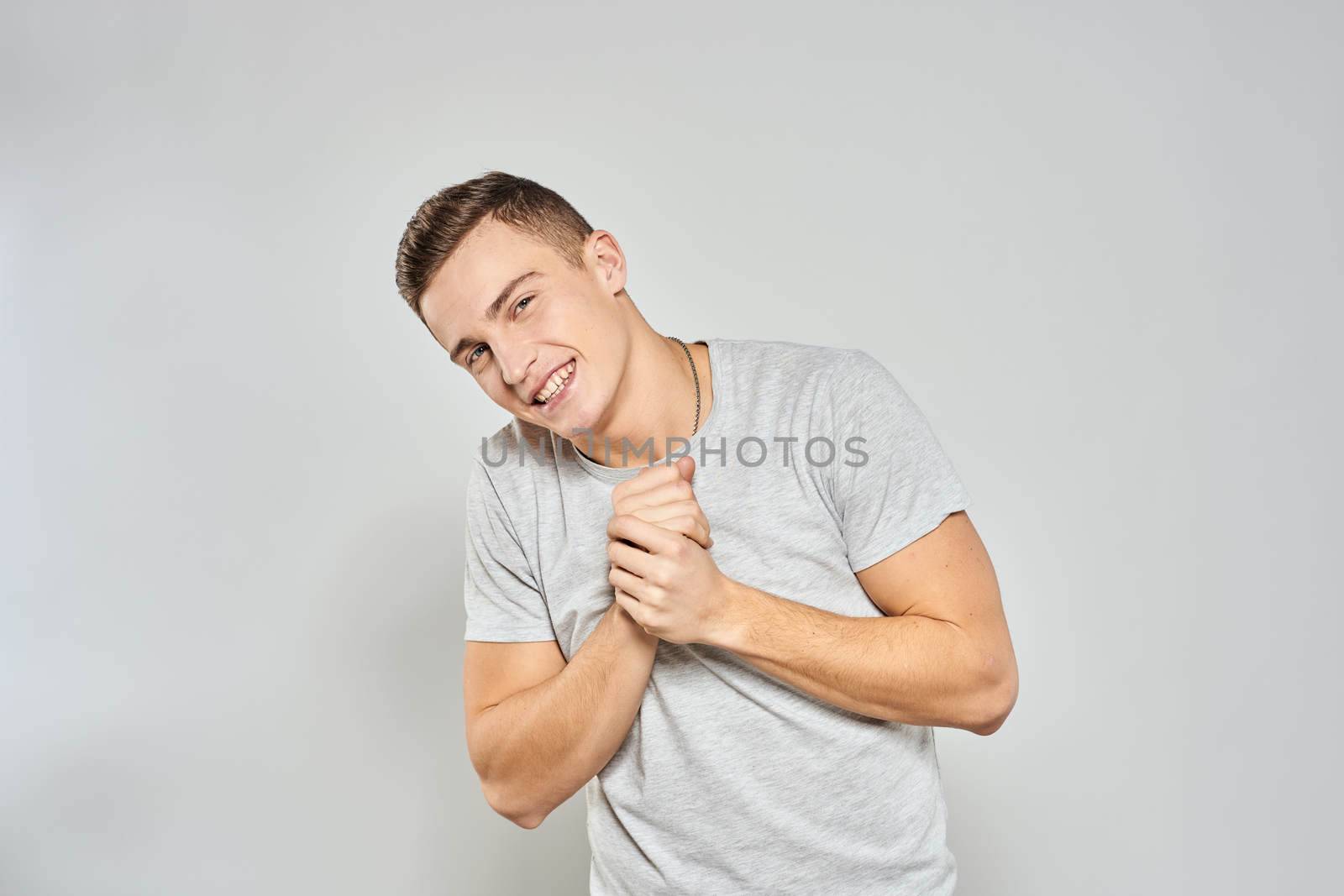 handsome man in light t-shirt cropped view emotion studio isolated background by SHOTPRIME