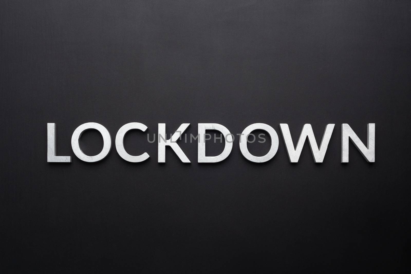 the word lockdown laid with silver metal letters on flat black background in directly above perspective.