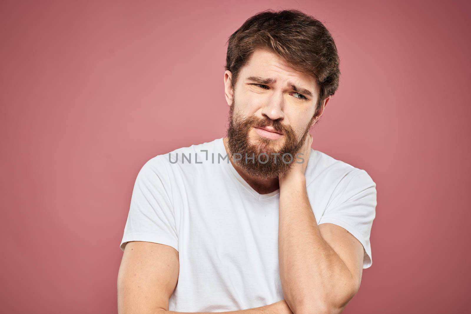 emotional man white t shirt sad facial expression pink background. High quality photo