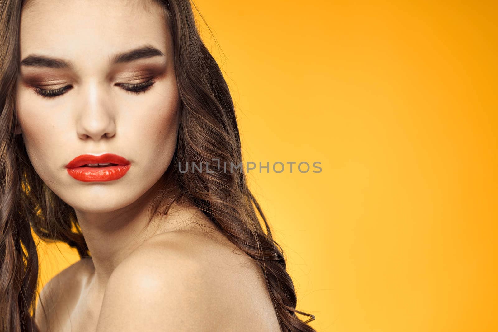 beautiful brunette red lips bare shoulders skin care yellow background. High quality photo