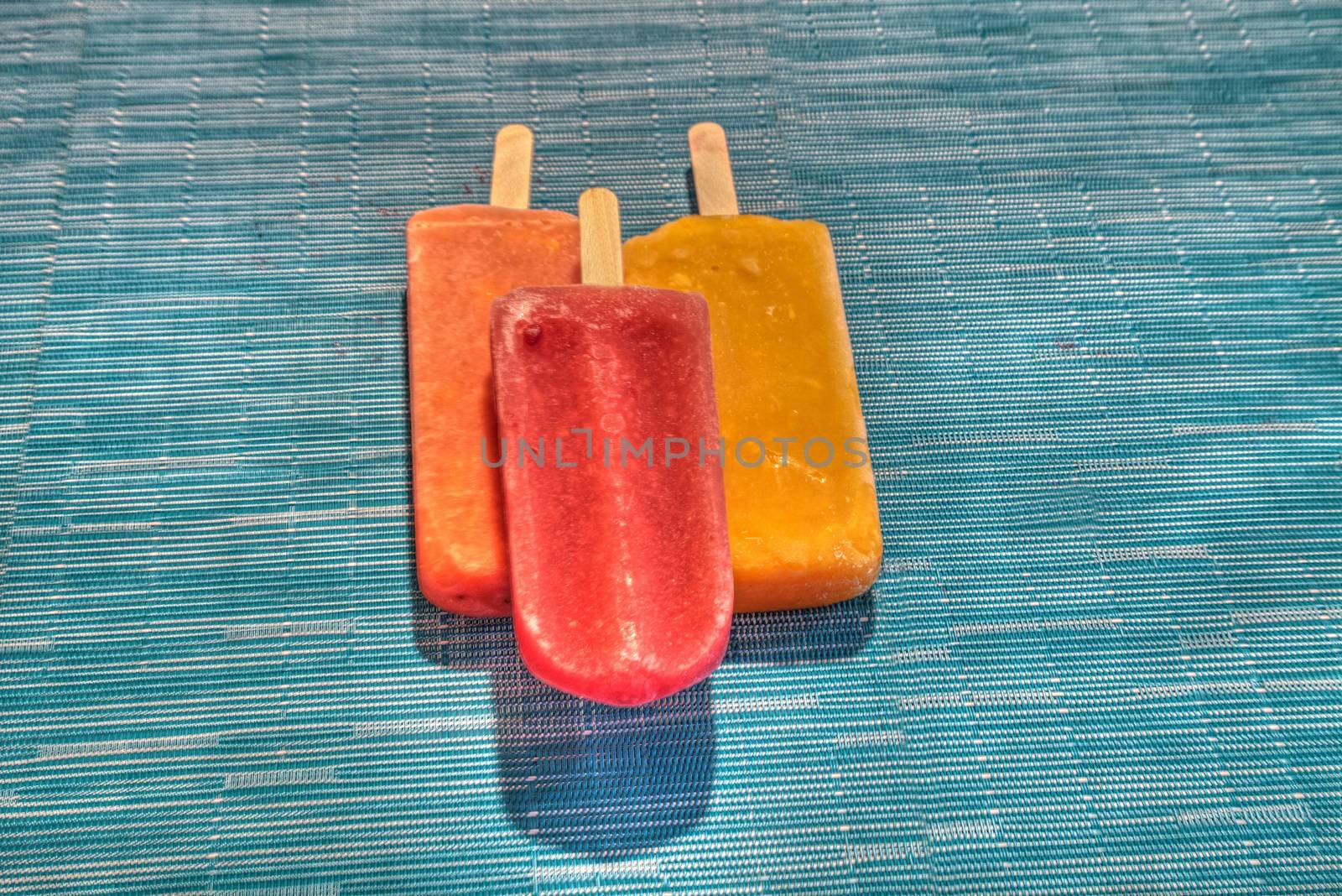 Fruit popsicles on an aqua blue background in summer by steffstarr