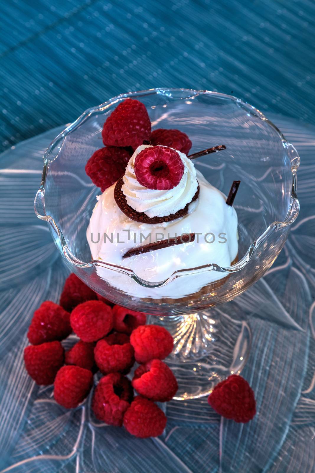 Dessert dish of cheesecake, shaved chocolate and raspberries on a glass plate.