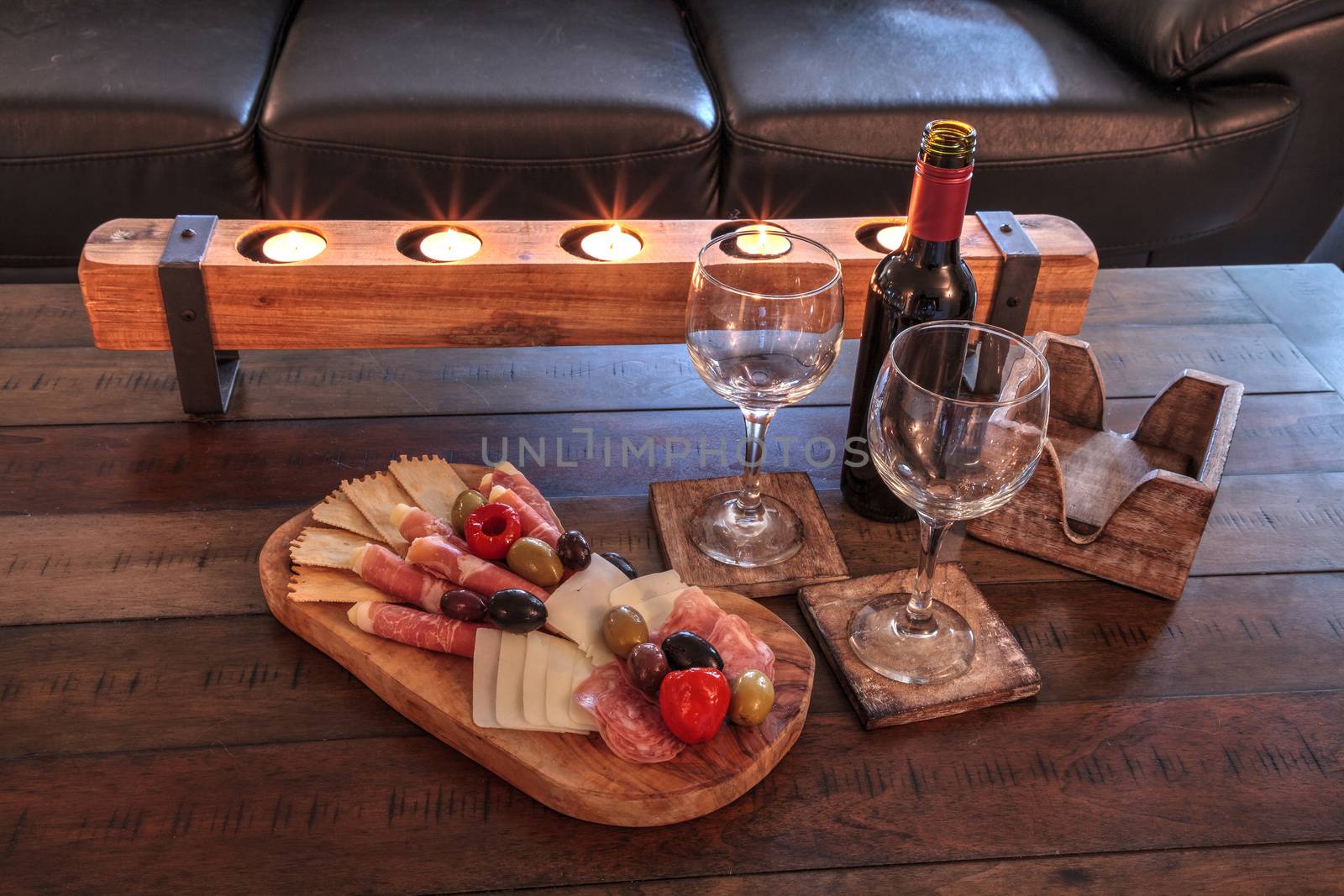 Red wine with Charcuterie board on rustic wood with candles behi by steffstarr