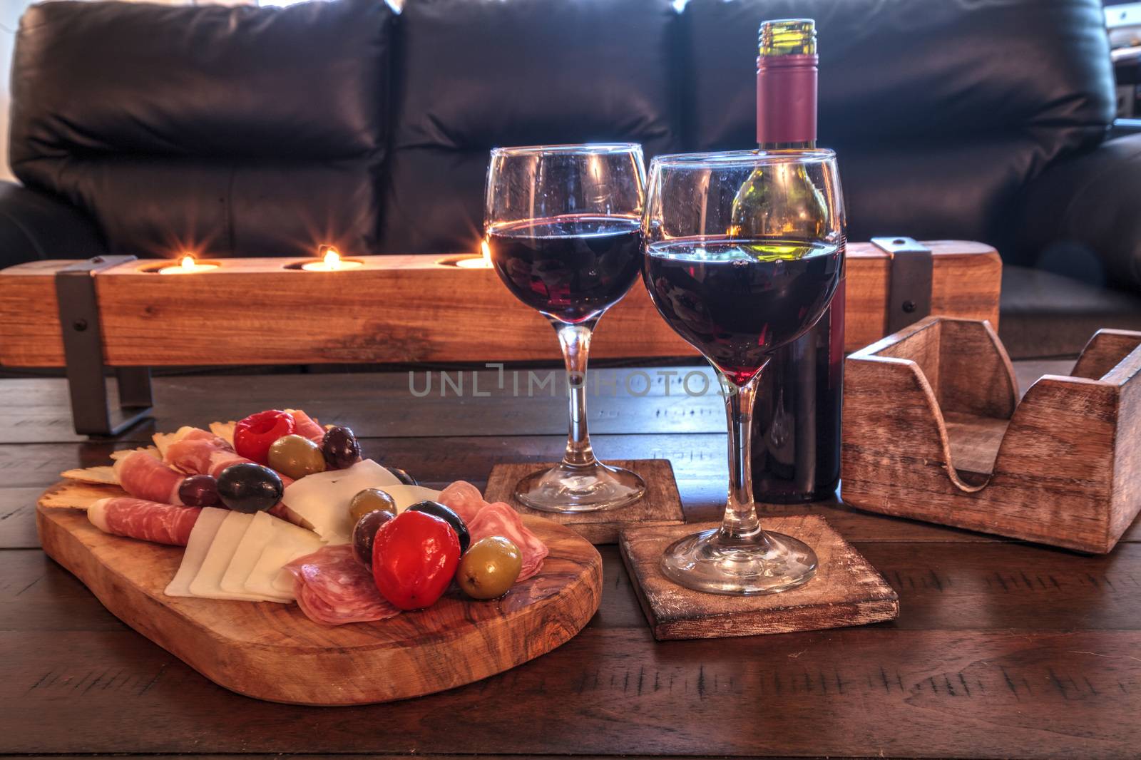 Red wine with Charcuterie board on rustic wood with candles behi by steffstarr