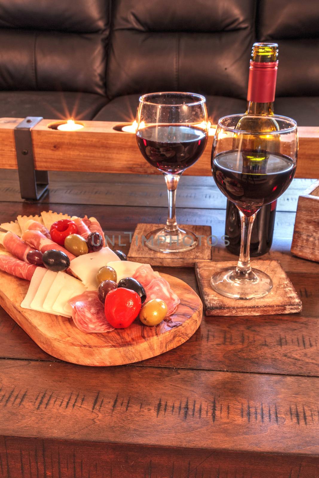 Red wine with Charcuterie board on rustic wood with candles behi by steffstarr