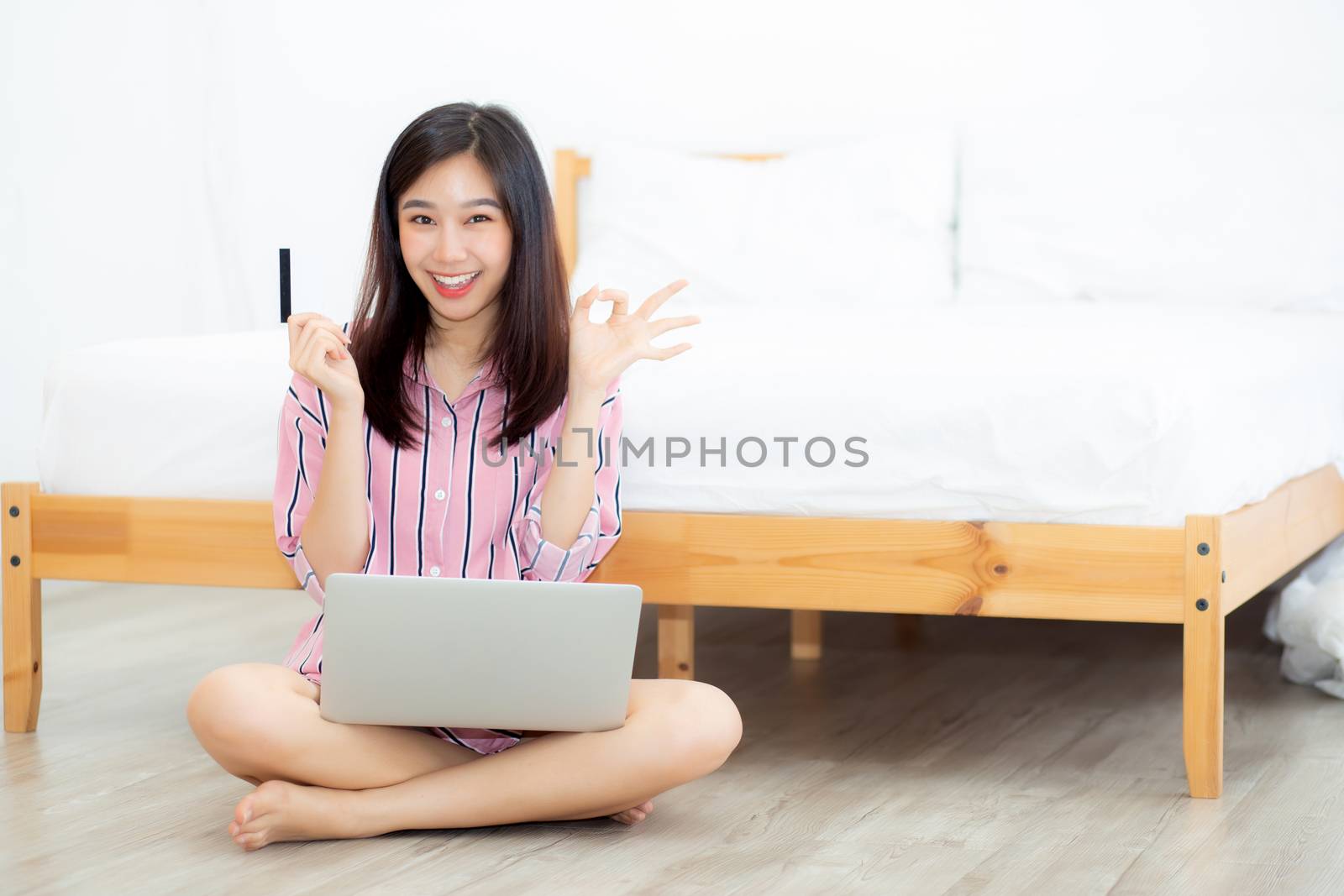 Beautiful portrait young asian woman sitting using credit card w by nnudoo