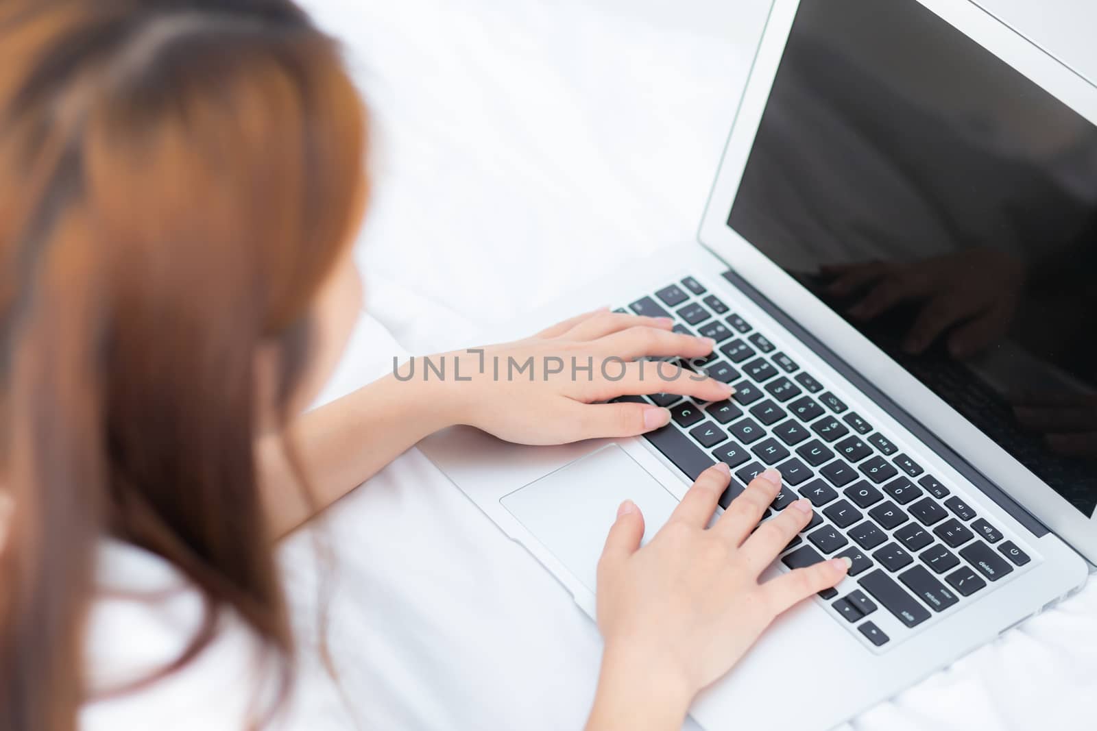 Closeup young asian woman using laptop for leisure on bedroom, girl working online with notebook freelance, business concept, top view.
