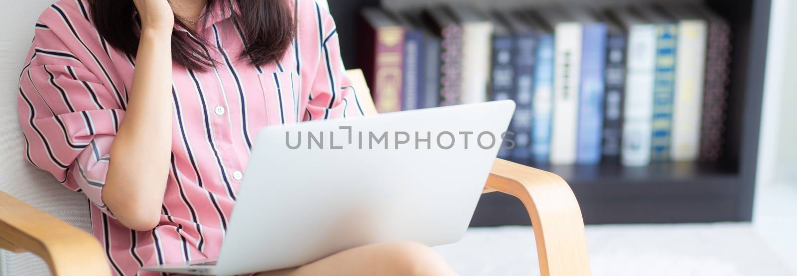 Banner website asian young woman working online laptop with smile and happy sitting on chair at living room, girl using notebook computer, business and success concept.