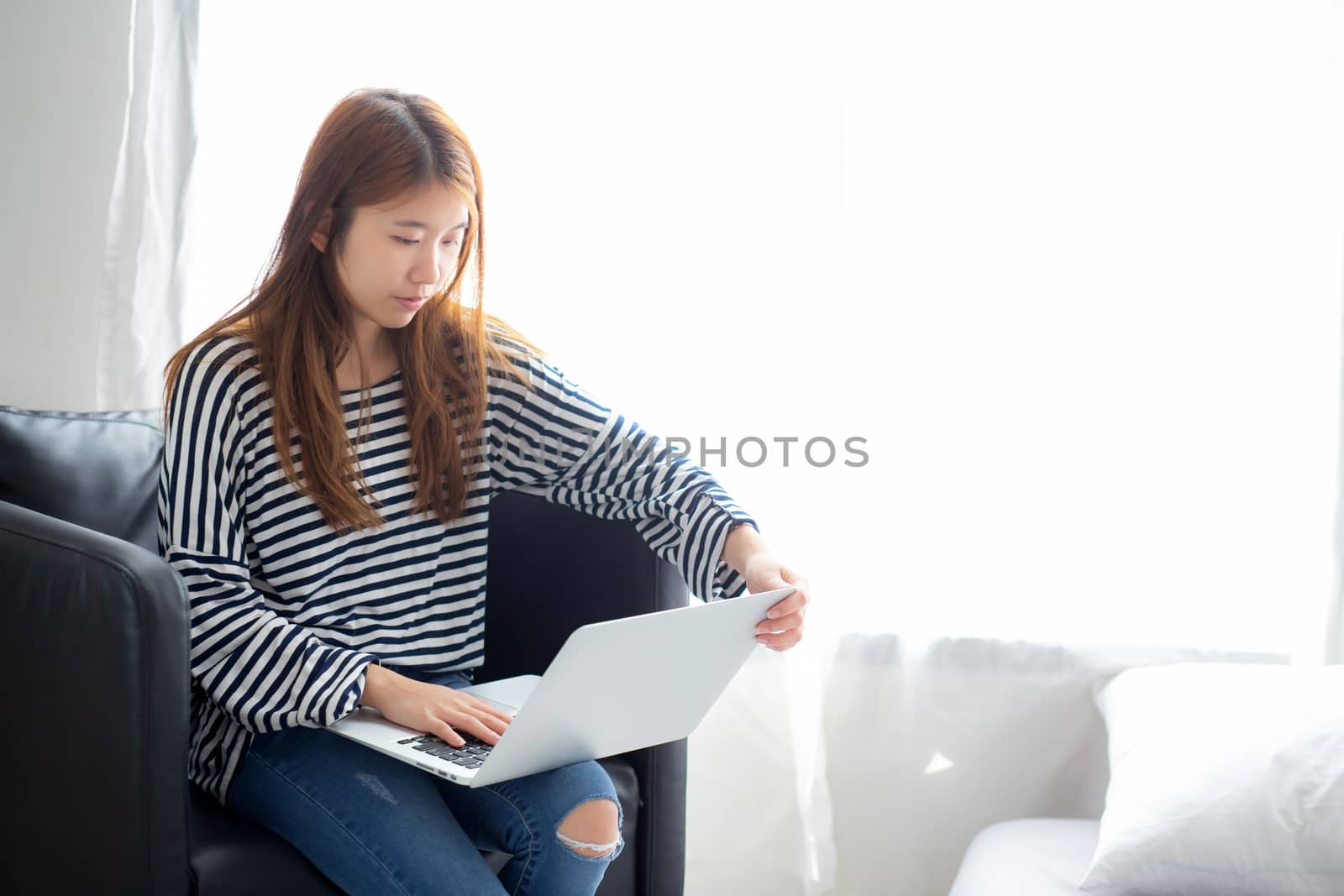 Beautiful of portrait young asian woman using laptop computer  for leisure on chair at living room, girl working online with notebook freelance, communication business concept.