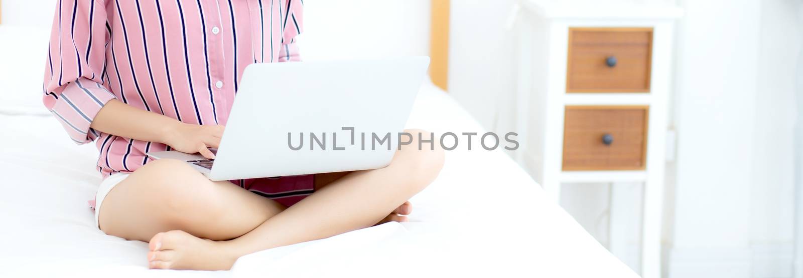Banner website asian young woman setting on bed using laptop com by nnudoo