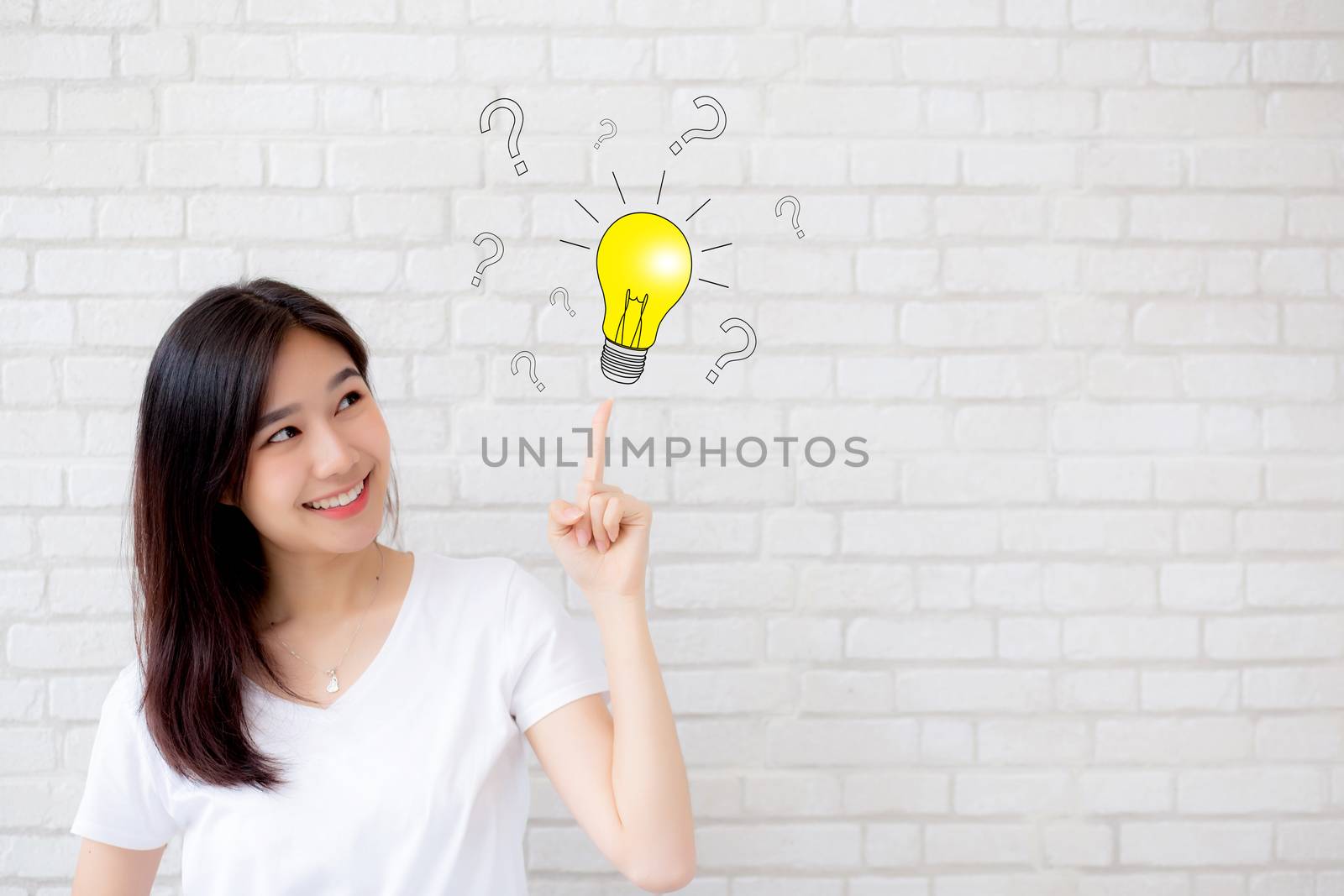 Asian woman thinking with drawing question mark for decision and have a idea and finger pointing light on grey cement texture grunge wall brick background, inspiration genius for success concept.