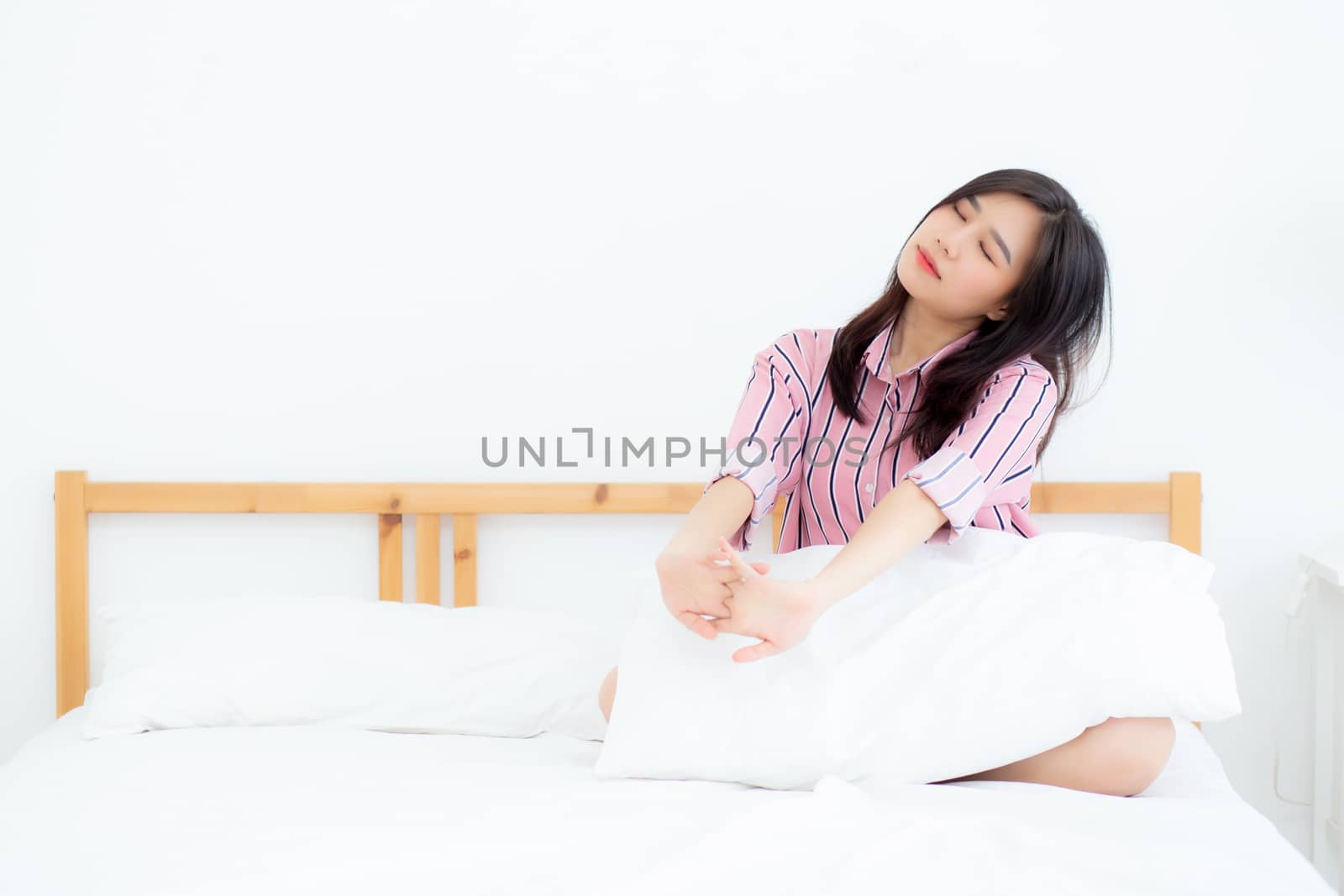 Beautiful of portrait young asian woman stretch and relax in bed after wake up morning at bedroom, new day and resting for wellness, lifestyle concept.