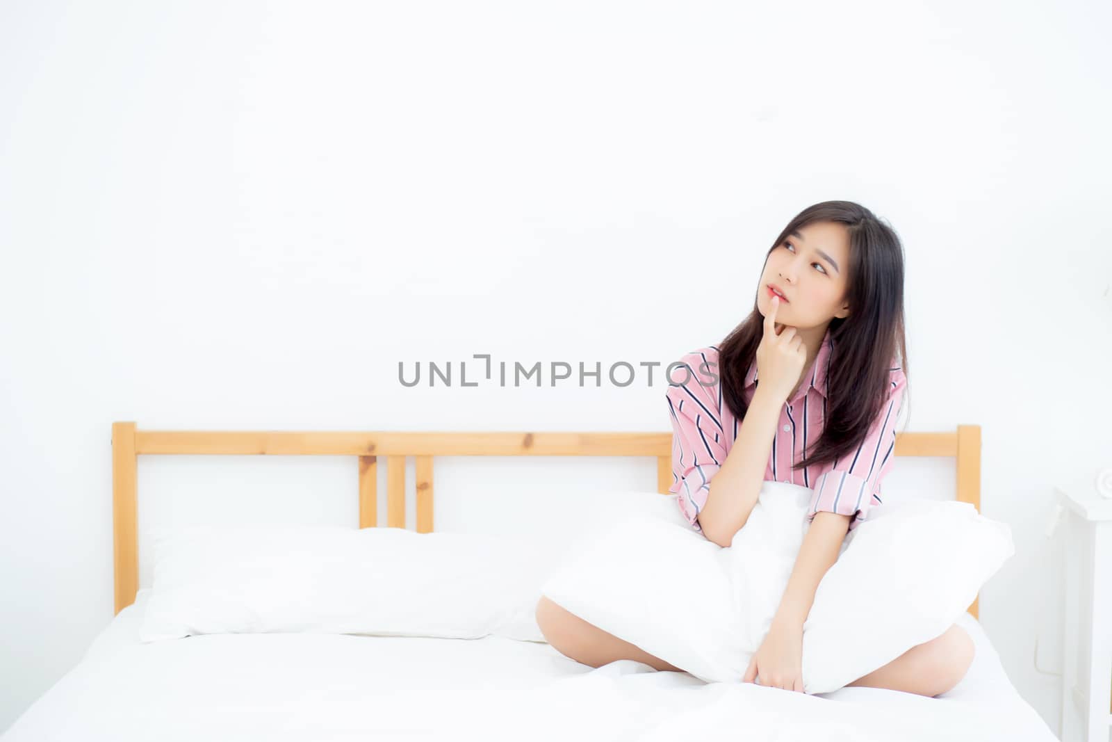 Beautiful portrait young asian woman smile confident thinking while wake up in the bedroom, girl sitting expression serious or doubts with idea, lifestyle and relax concept.