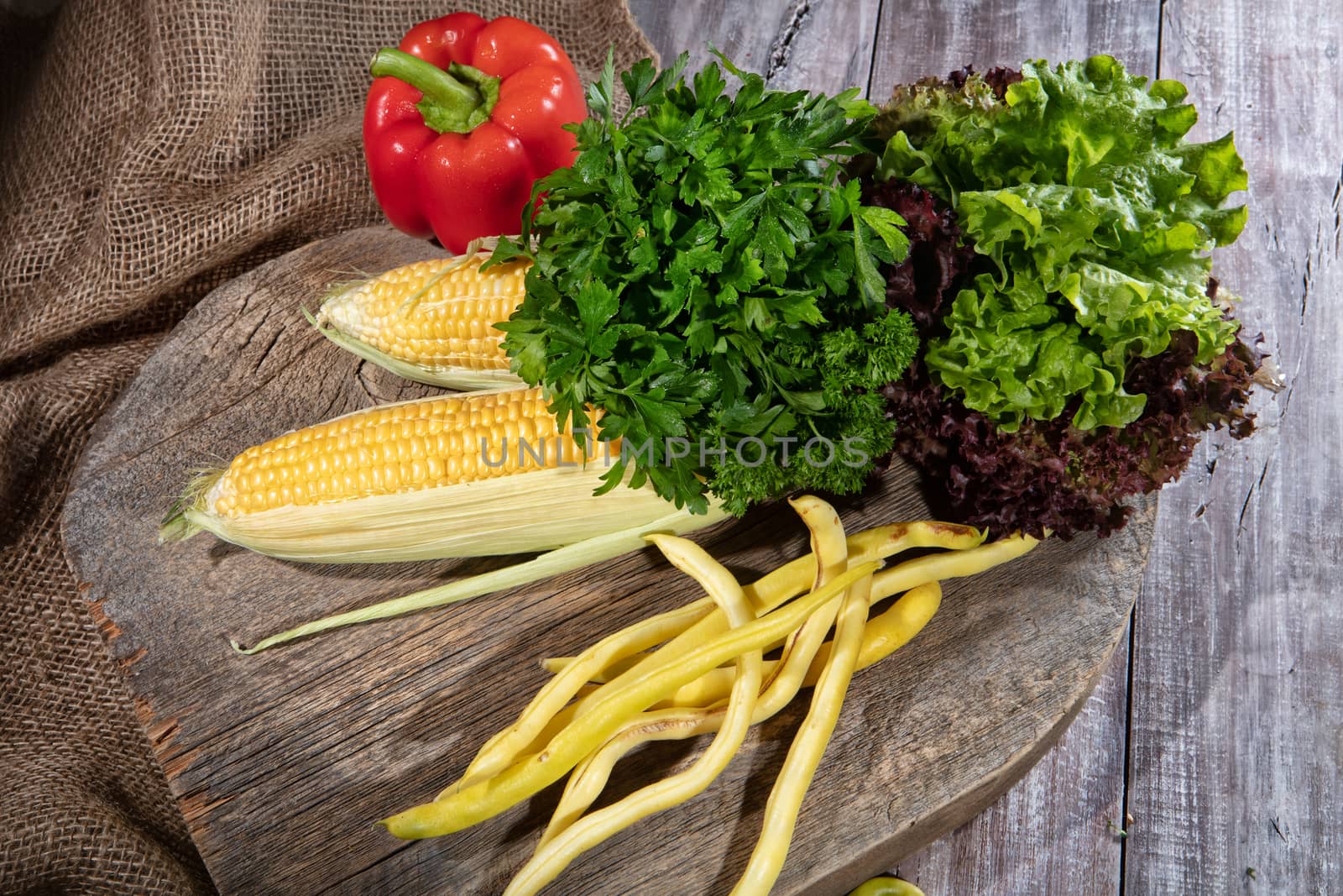 Maize, greenery, pea and tomato on a wooden table