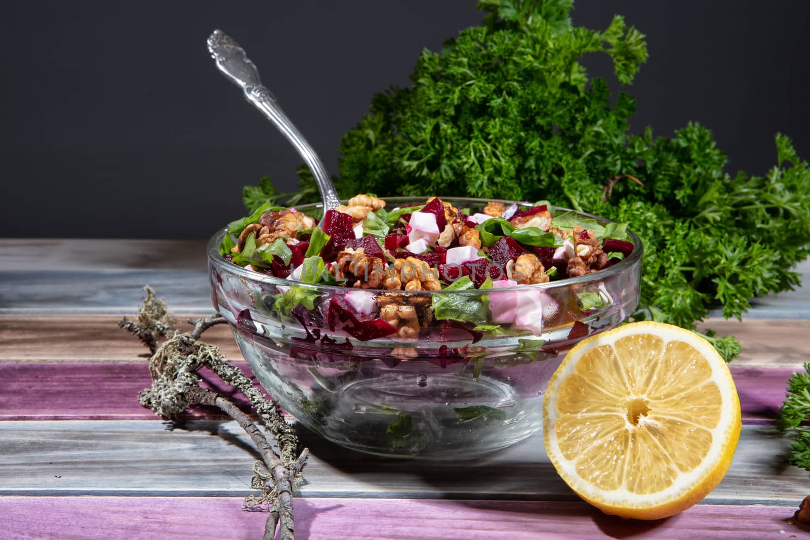 Plate with sald, lemon and greenery on a wooden table