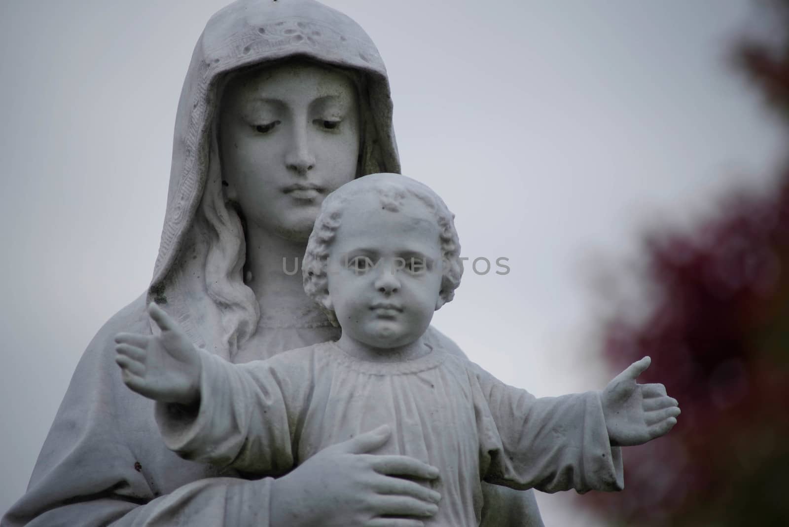Beautiful old cemetery statue of Mary and Jesus as the Christ Child, defocused background with copy space.