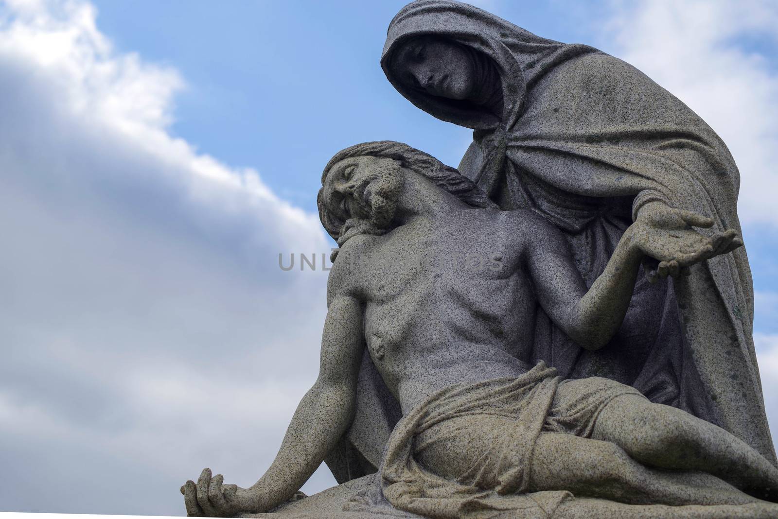 Cemetery statue, Jesus and Mary pieta against a blue sky by marysalen