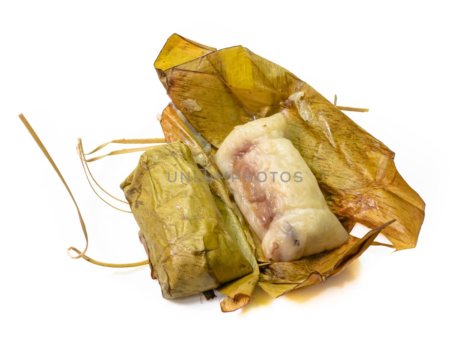 The close up of Thai steamed sticky rice with coconut milk and banana (Khao Tom Mud) wrapped by banana leaf on white background.