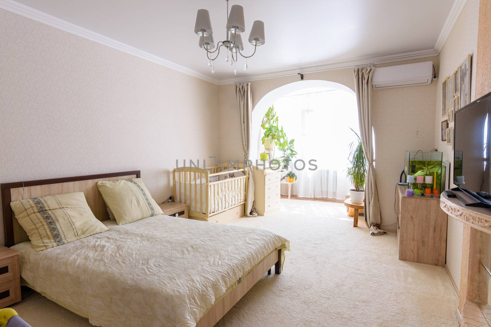 Nice interior of a bedroom combined with a balcony and a crib for a newborn baby by Madhourse