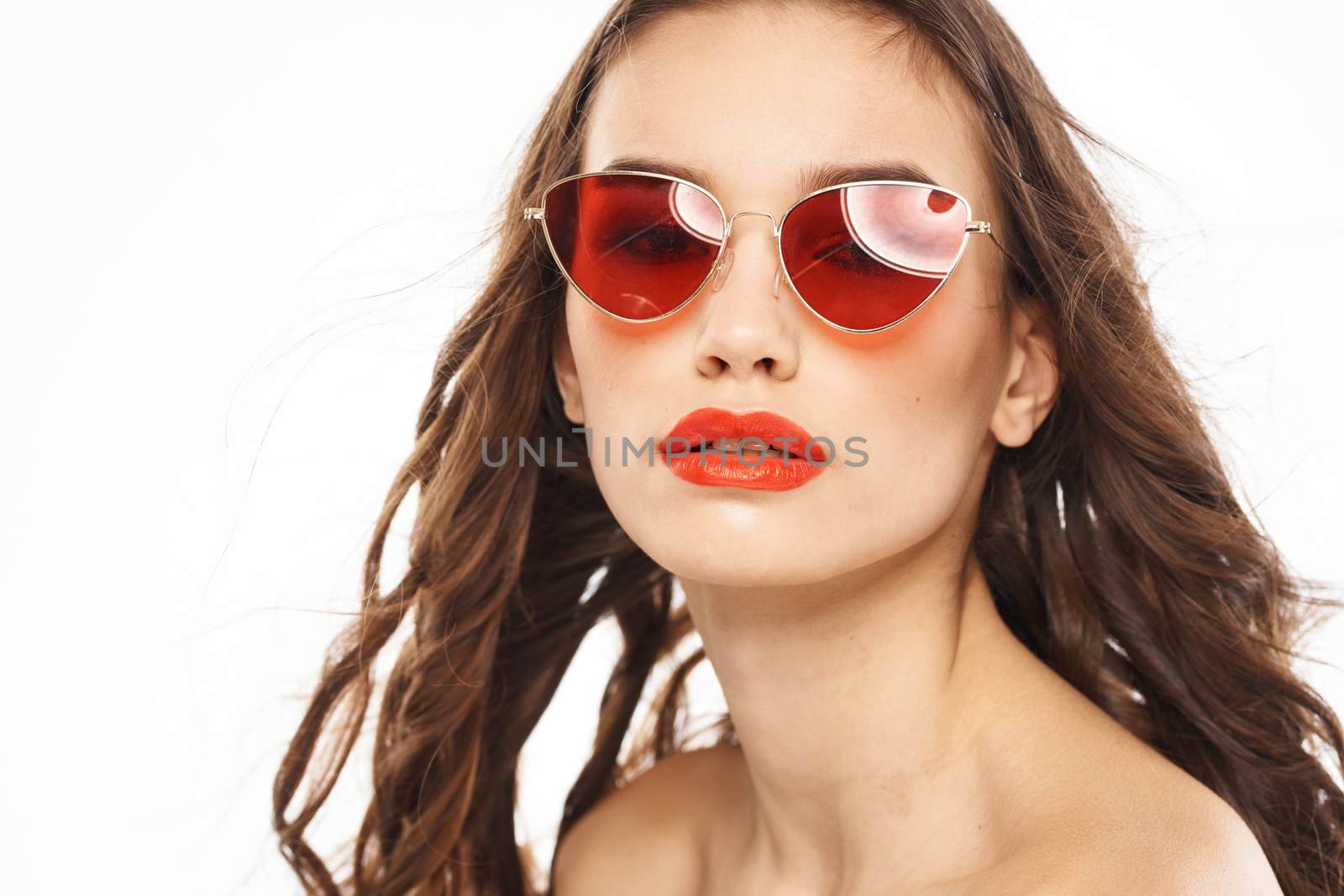 Portrait of brunette woman in sunglasses naked shoulders light background. High quality photo