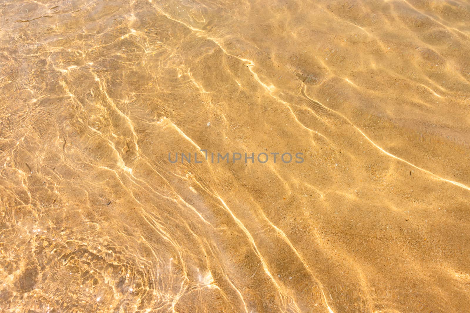 Ripples of water waves reflecting texture on a sandy beach bottom by nilanka