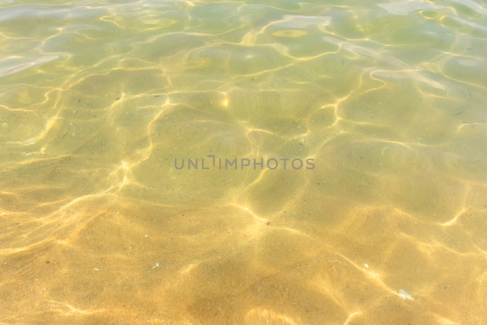 Ripples of water waves reflecting texture on a sandy beach bottom by nilanka