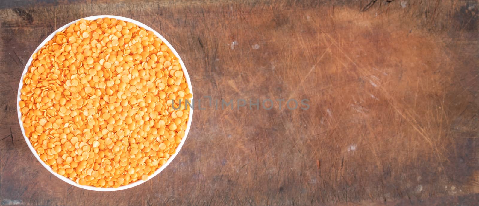 Bowl of uncooked dhal on wooden board