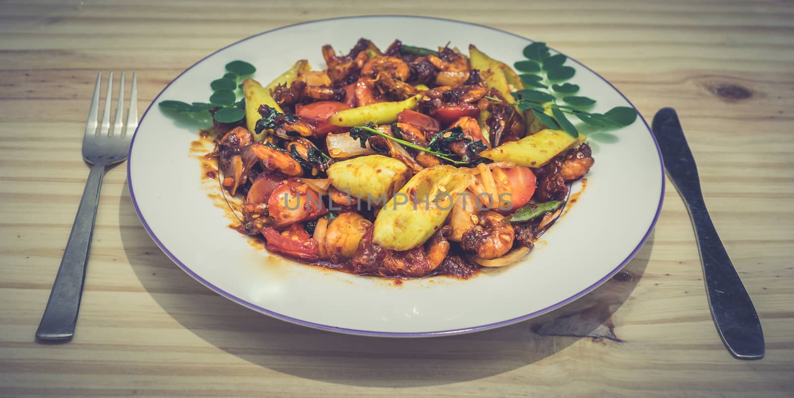 Plate of deviled prawns with fork and knife by nilanka