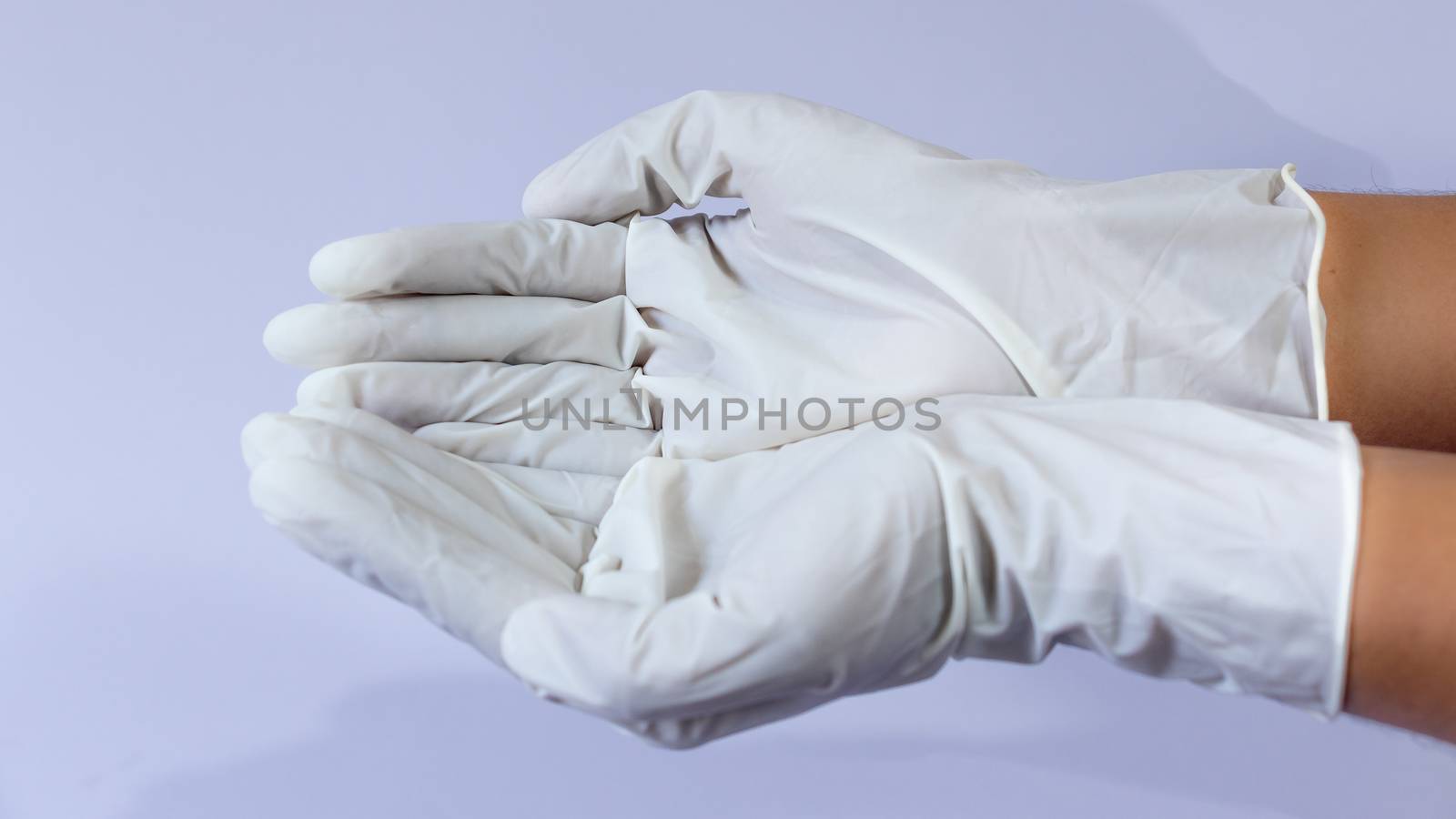 Female doctor wearing medical latex gloves in both hands together by nilanka