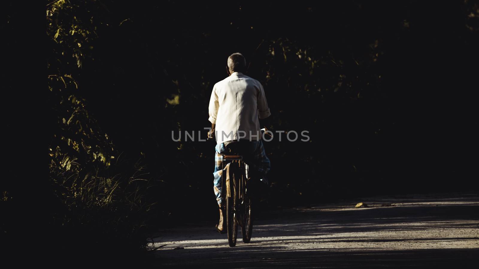 old man riding bicycle in rural village