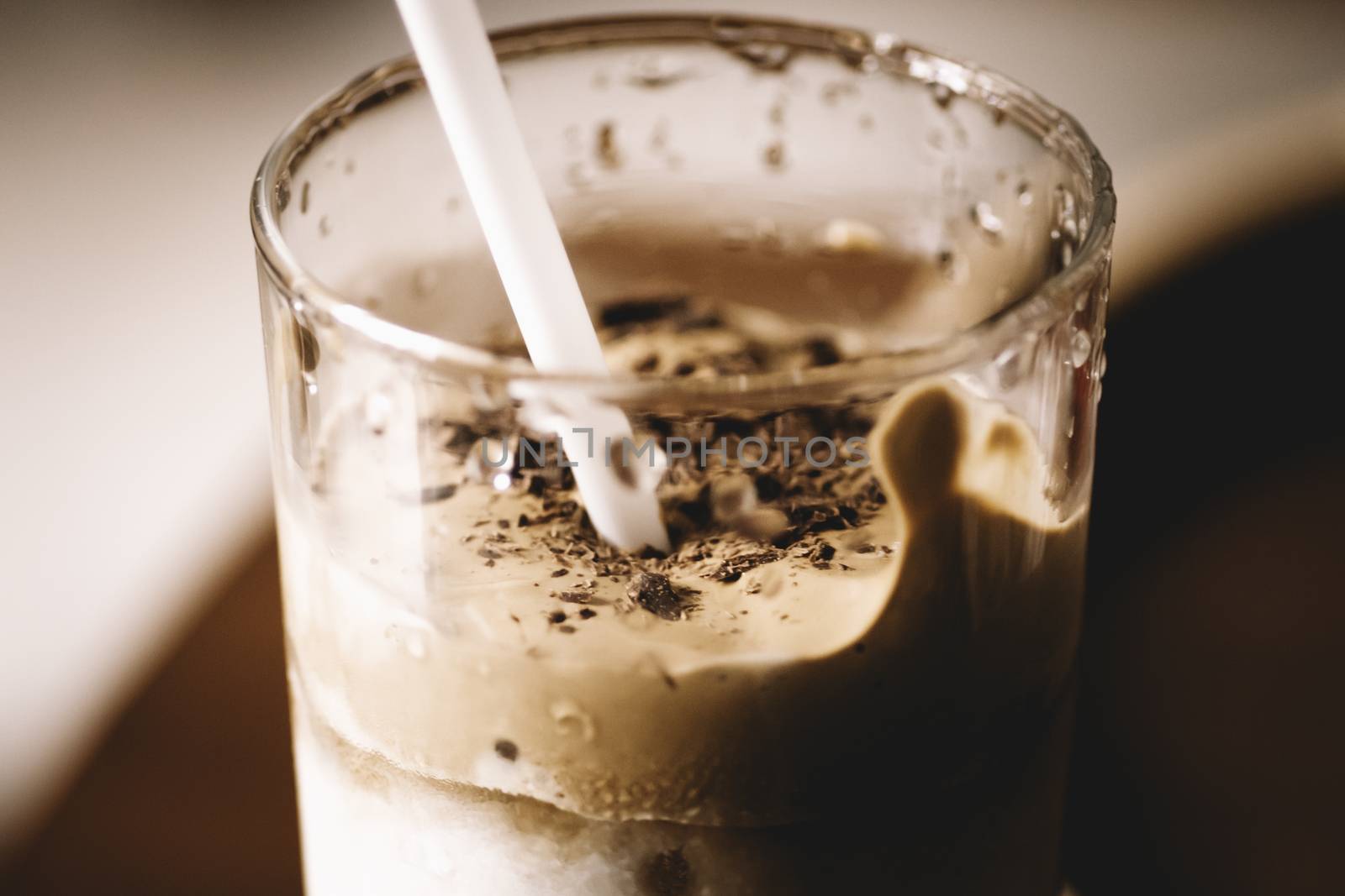 home made Dalgona coffee glass with straw side close up photo by nilanka