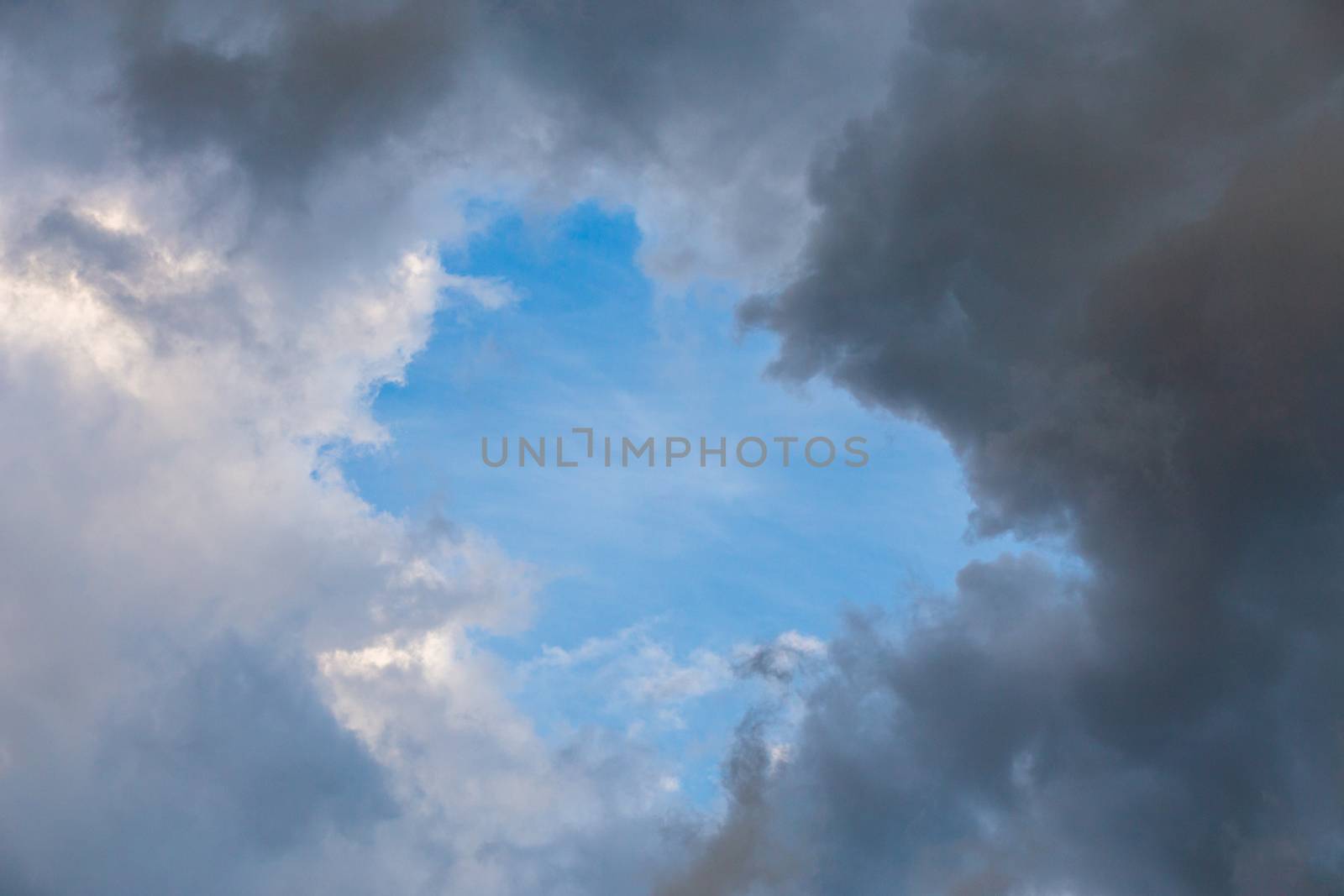 natural blue sky window in clouds, round gap in solid summer clouds.
