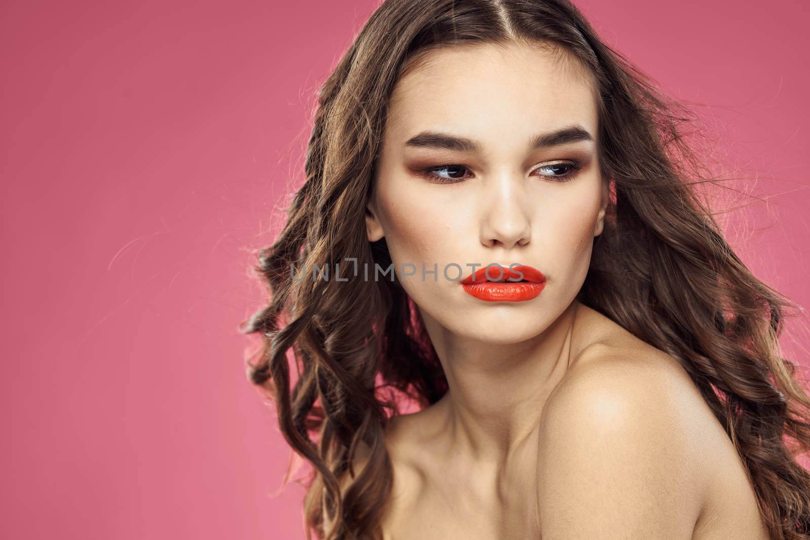 Attractive woman fashionable hairstyle bared shoulders and red lips pink background. High quality photo