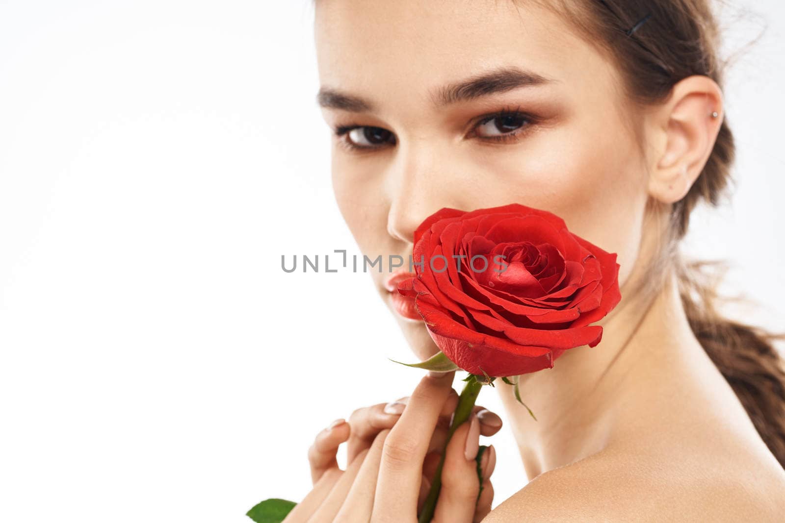 Beautiful woman with red rose near face makeup naked shoulders portrait. High quality photo