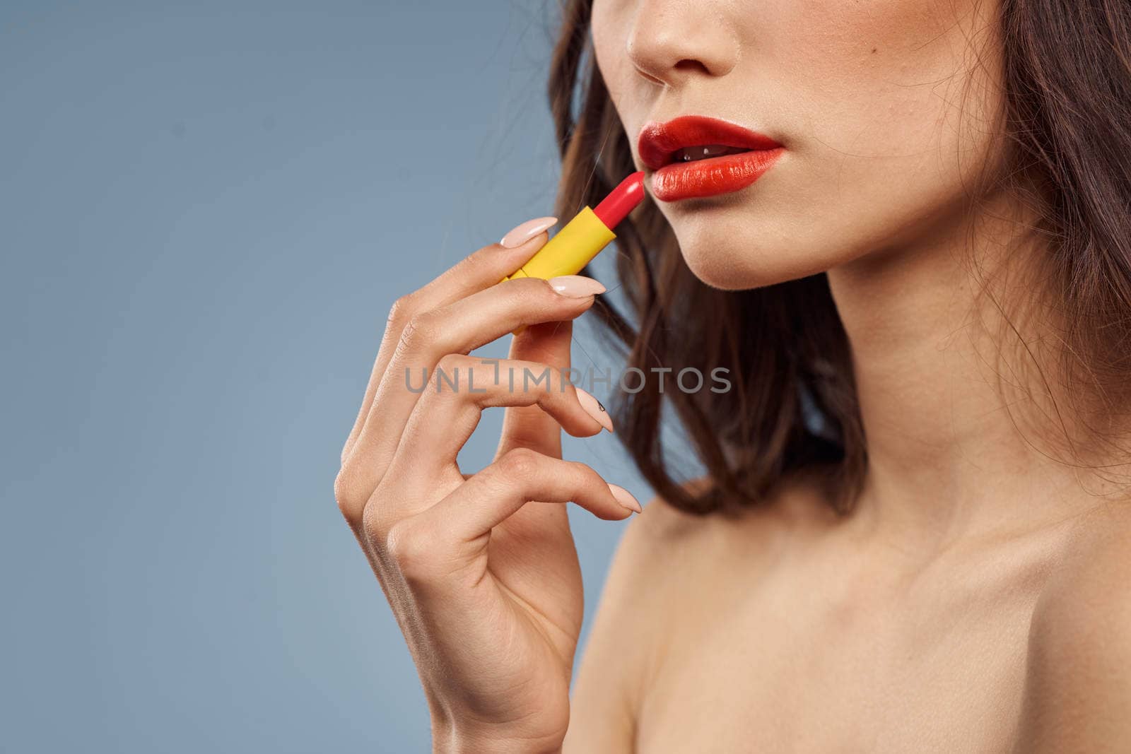 Woman with lipstick on a gray background brunette makeup with eye shadow on the eyelids. High quality photo