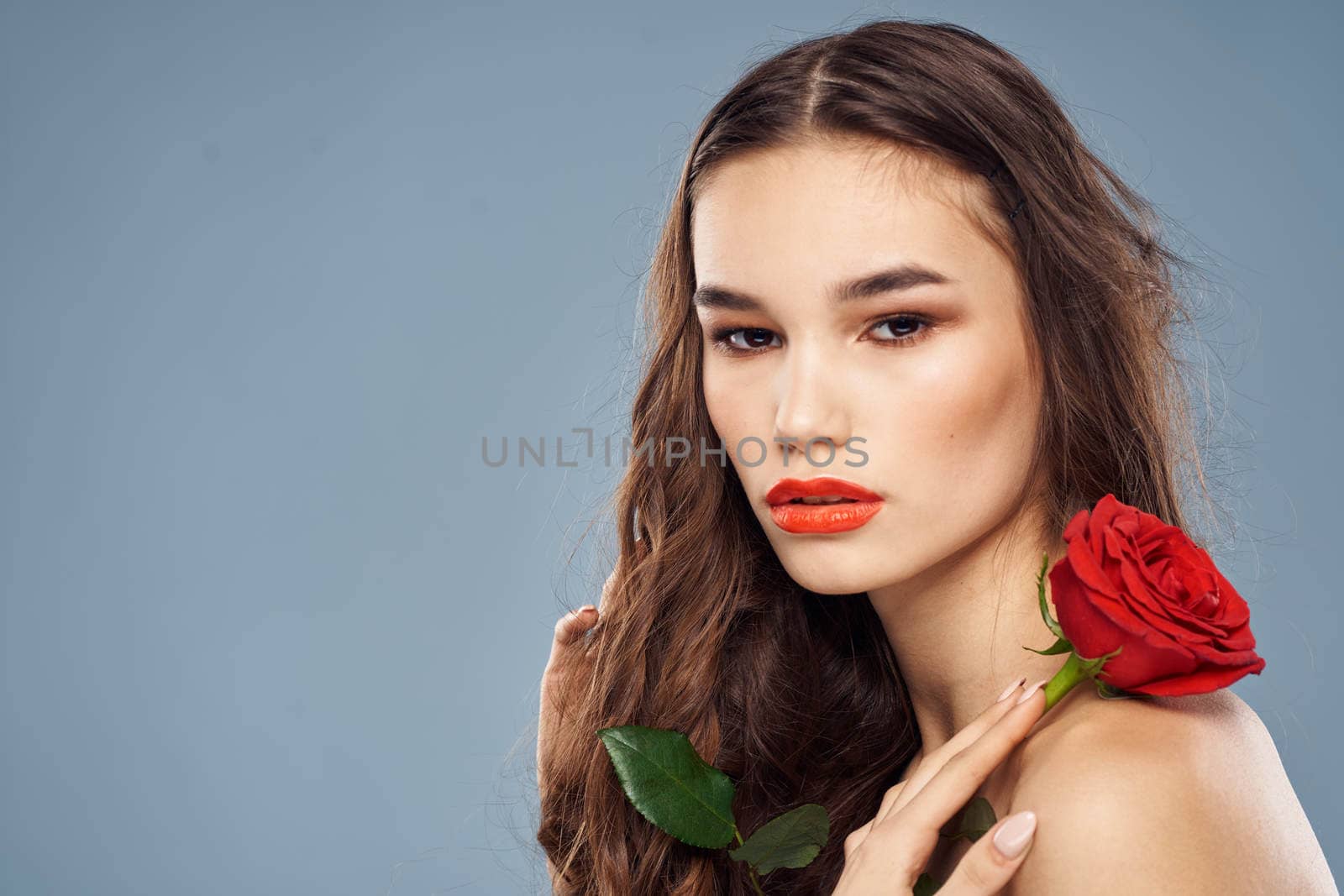 woman with a rose in her hands naked shoulders evening makeup red lips. High quality photo